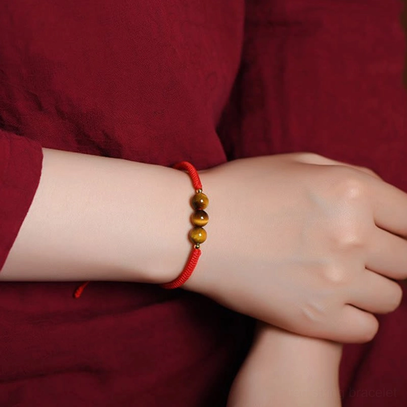 Tiger eye red string bracelet artistic flat lay composition on fabric background