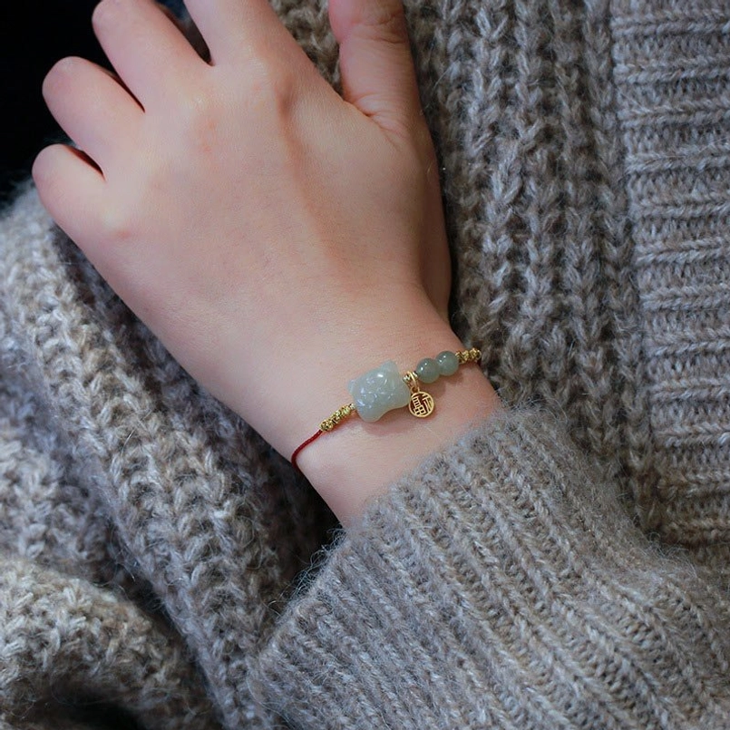 Zodiac tiger jade red string bracelet worn on wrist showing side view with gold fu charm and jade beads