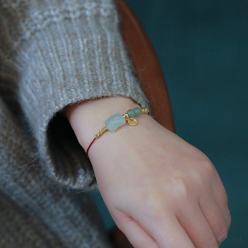 Zodiac jade red string bracelet front view on wrist displaying light green jade tiger charm and gold metal details