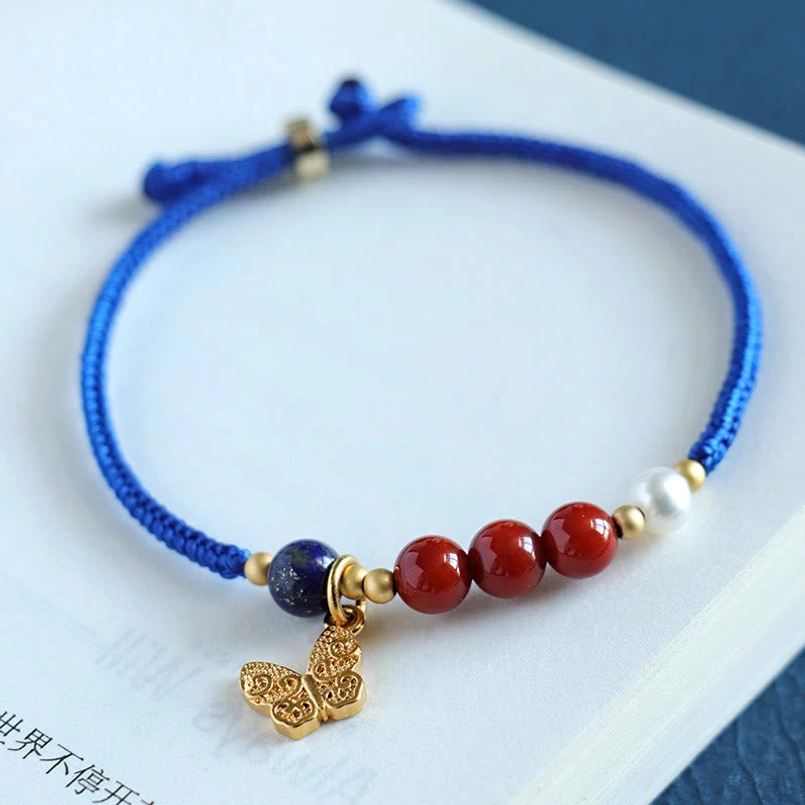 Traditional woven blue string beaded bracelet with red gem beads and butterfly charm
