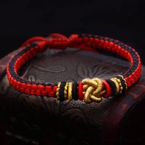 Red gold true love knot handmade bracelet with golden knot charm on dark fabric