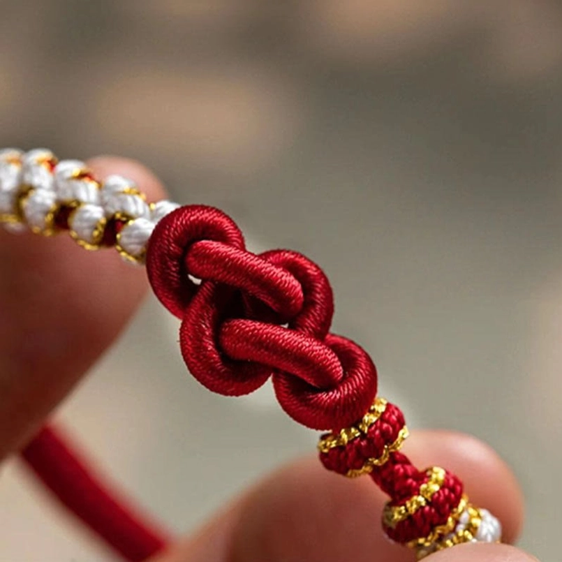 Extreme close-up of true love knot woven detail with red rope texture and gold beaded accents