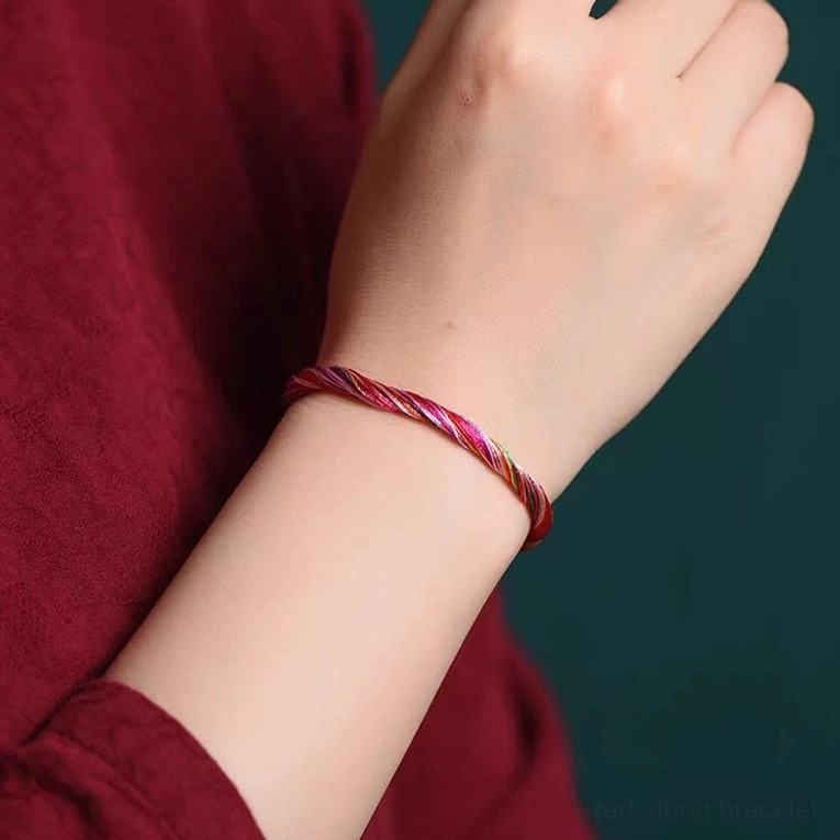 Slim twisted five color red string bracelet close up on adult wrist