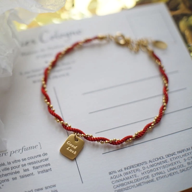 Overhead view adjustable red cord bracelet with twisted red and gold cord design