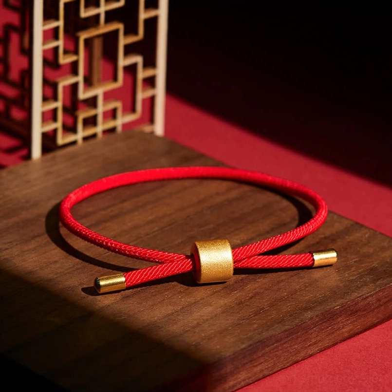 Adjustable twisted red woven cord bracelet matte gold slider on wooden board