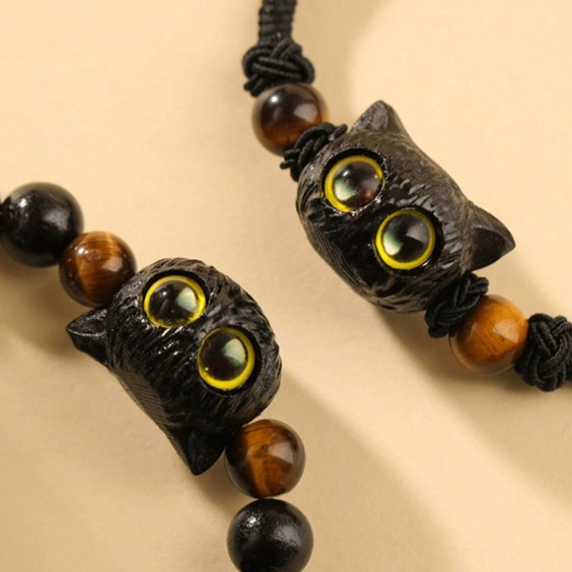 Two ebony cat head red string bracelets flat lay on beige background