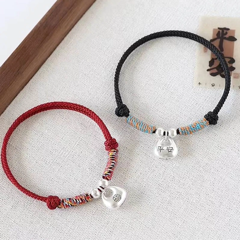Pair of red and black Fu character lucky bracelets with Ping An greeting card on linen