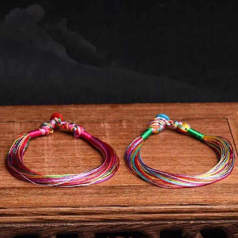 Two matching colorful red string bracelets flat lay on wooden table