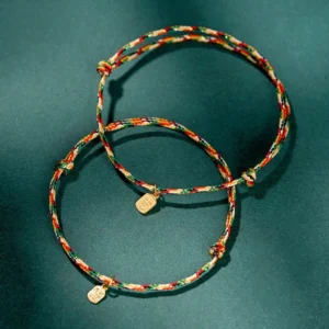 Two multicolor braided Fu character lucky red string bracelets on dark green background