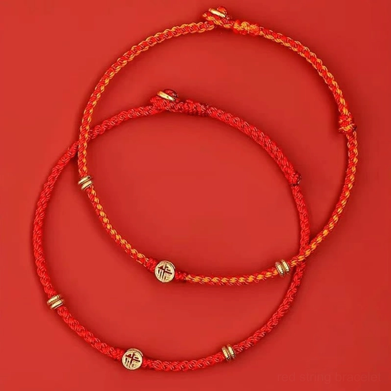 Two red string Fu charm luck bracelets high angle view on red background