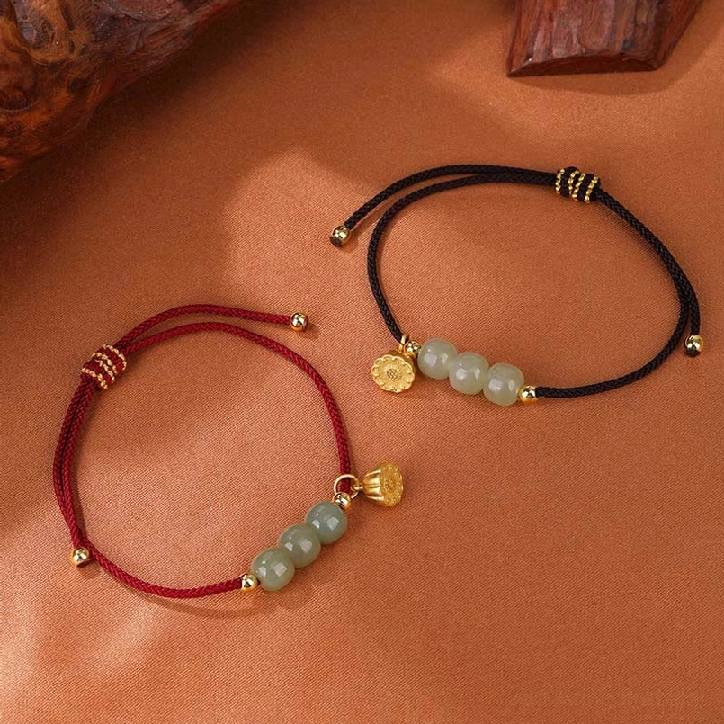 Red and black Hetian jade lotus pod bracelets displayed side by side on wooden table