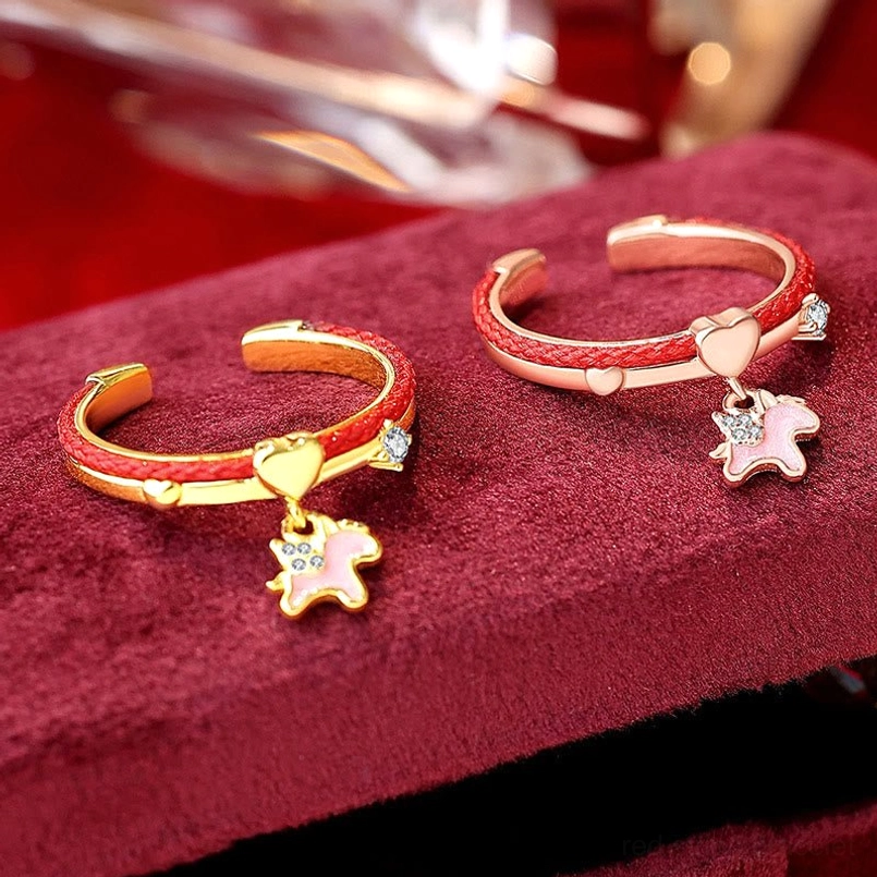 Two unicorn charm adjustable rings with red woven cord in rose gold and gold-tone finishes