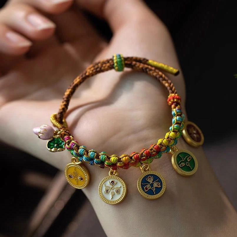 Tibetan enamel pendant bracelet held in palm showing multicolor rope and charm details