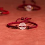 White agate peace buckle red string bracelet side overhead view on red textile tabletop