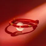 White chalcedony peace buckle red string bracelet front overhead view on red satin background