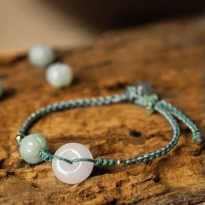 White jade peace buckle braided bracelet with green pumpkin bead on natural wooden surface