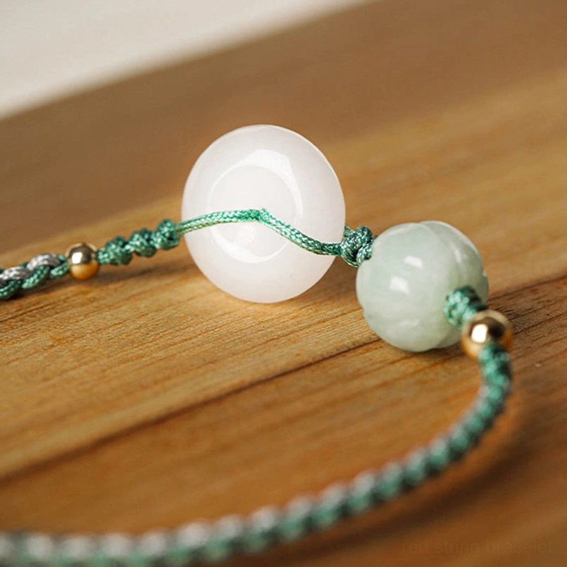 Close-up detail of white jade peace buckle with green pumpkin bead and gold accents