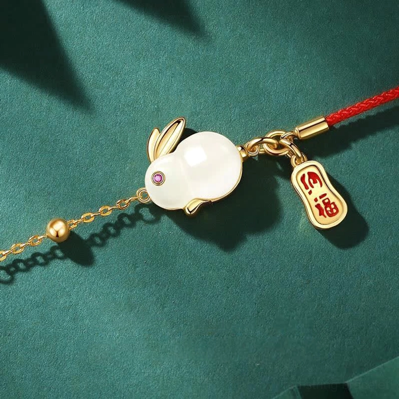 White jade rabbit charm close up with gemstone inlaid eye and fortune tag