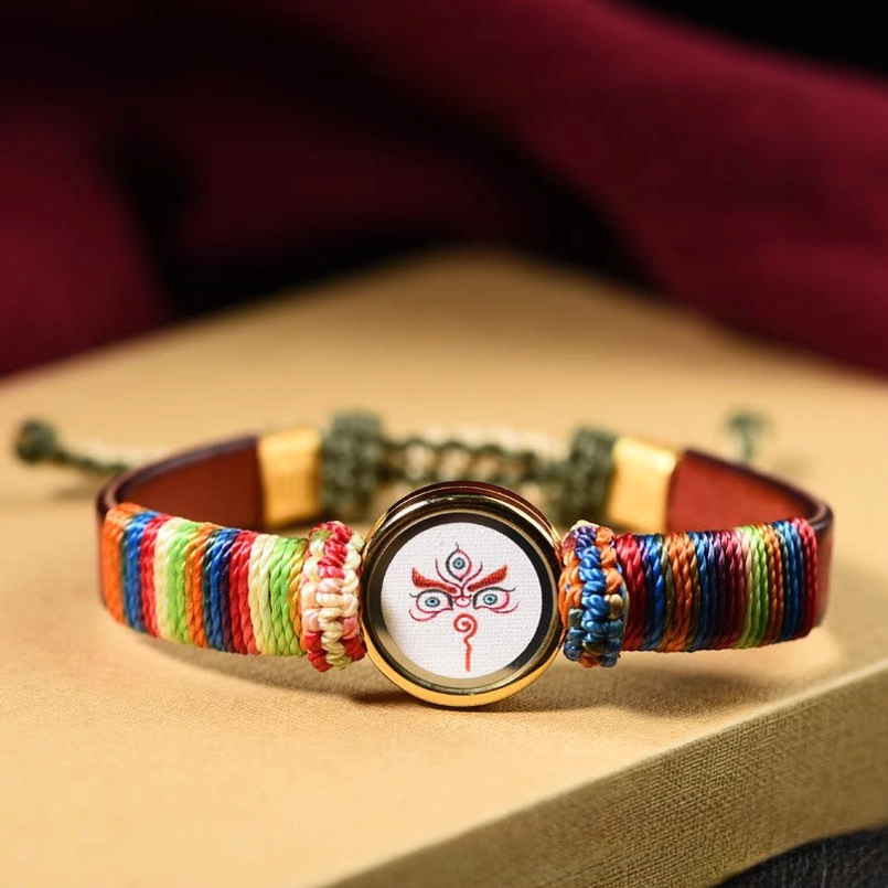 White Jambhala eye blessing bracelet with rainbow woven cord and gold frame
