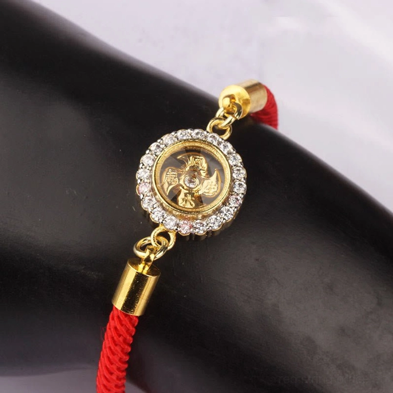 Red string feng shui rotatable windmill bracelet close-up on model hand showing intricate engraved amulet detail