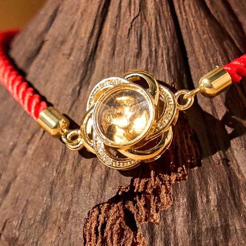 Close up of rhinestone adorned copper brass plum windmill red string bracelet