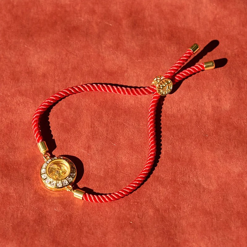 Copper brass red string bracelet with zirconia trim and decorative bead clasp on velvet