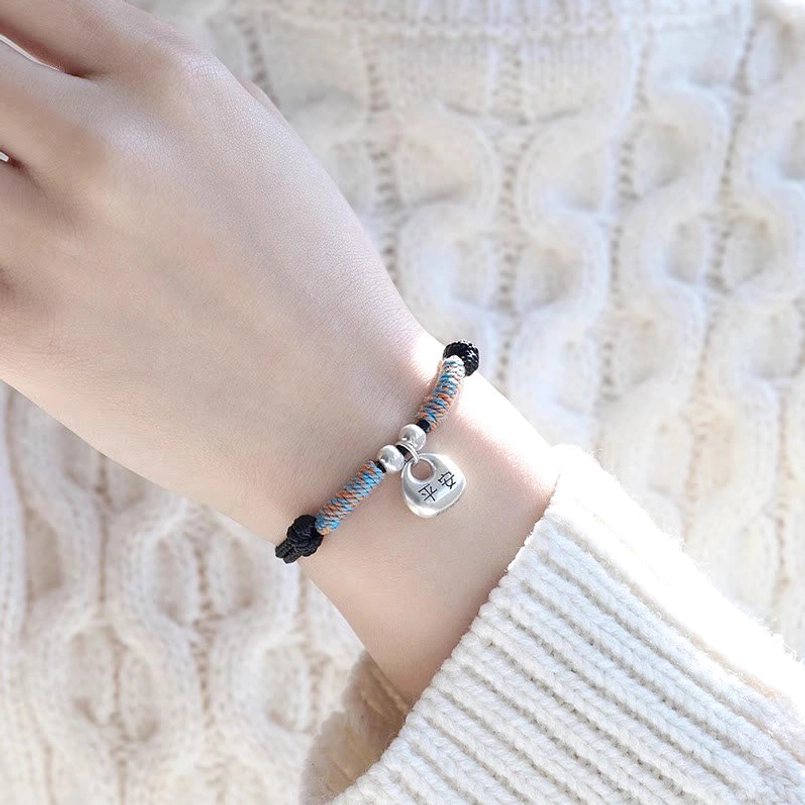 Close up of black Fu charm lucky bracelet worn on wrist with cream sweater
