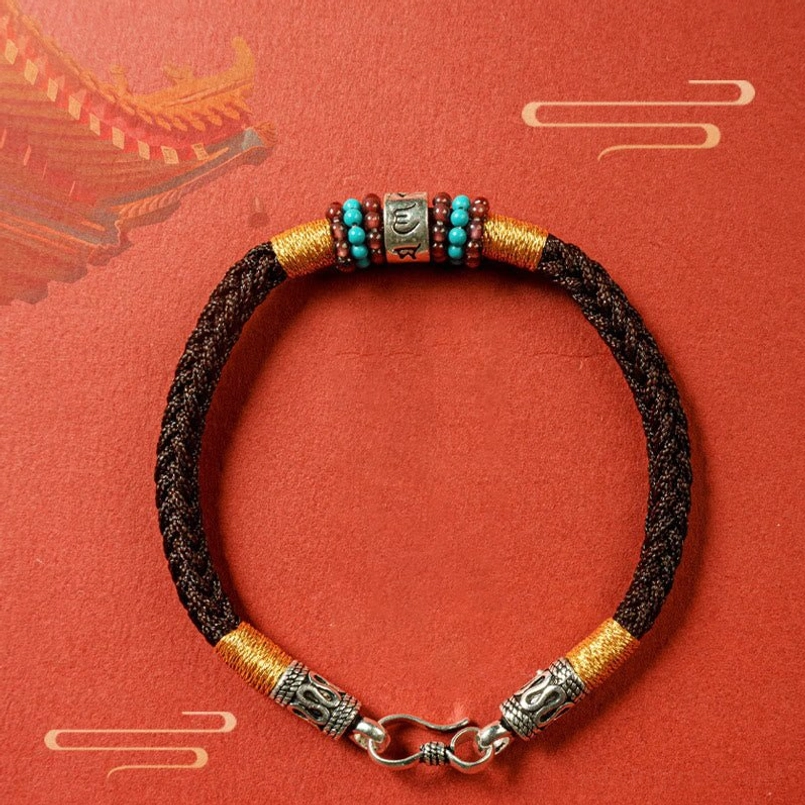 Black braided Tibetan bracelet on red cloud pattern background with silver accessories