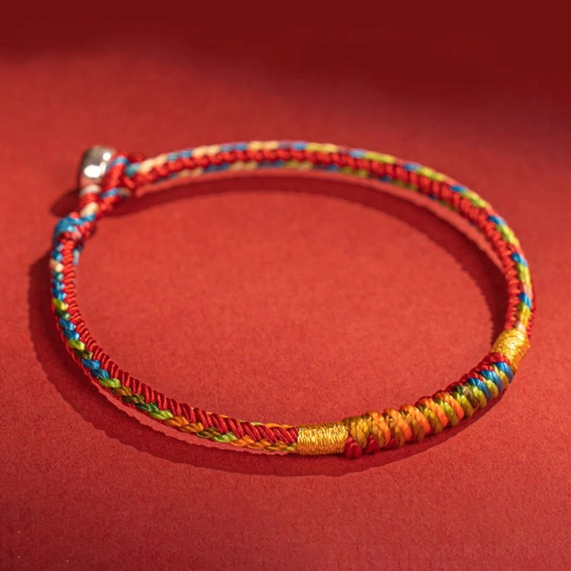 Woven string luck red string bracelet with silver screw clasp on red fabric background