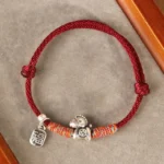 Year of the Horse Fu character sterling silver red string bracelet handcrafted top-down flat lay on velvet with wooden frame