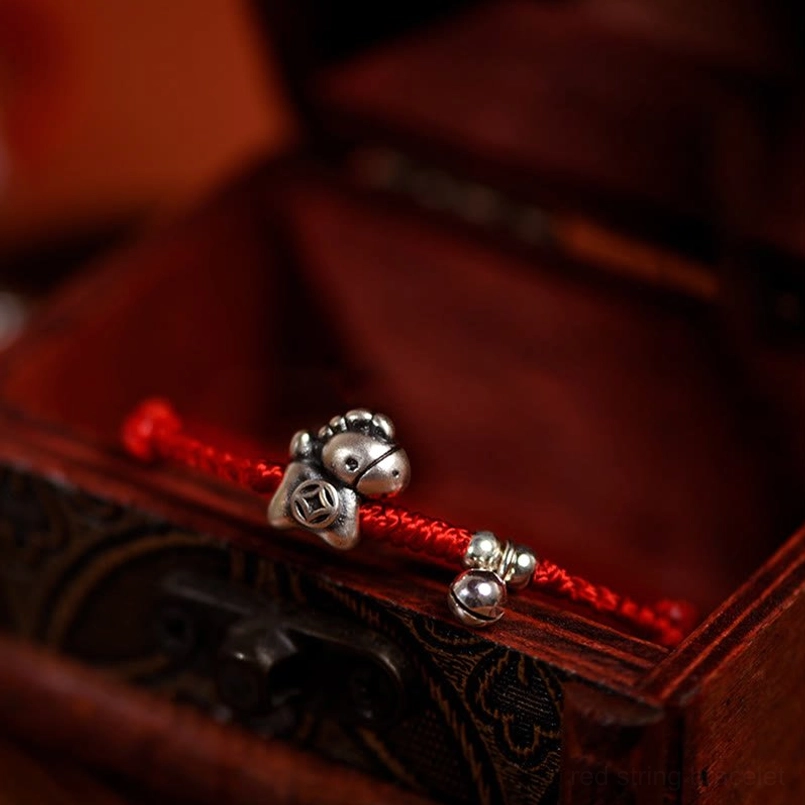 Adjustable red string bracelet with silver horse charm worn on wrist lifestyle photo