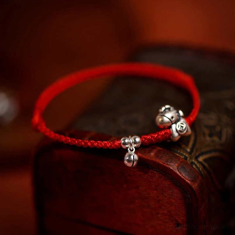 Year of the Horse sterling silver red string bracelet with horse coin charm and bell on wooden backdrop