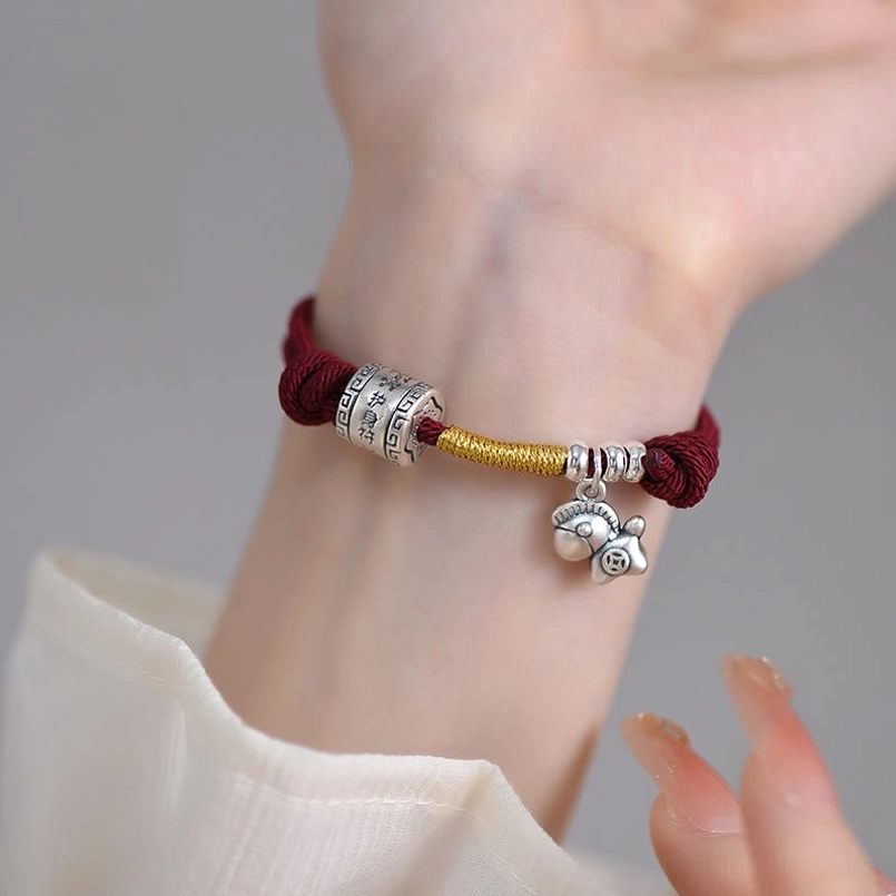 Red string silver horse bracelet front view on wrist with light neutral background