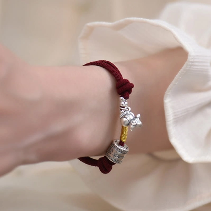 Year of the Horse red string bracelet being worn on wrist against white shirt fabric
