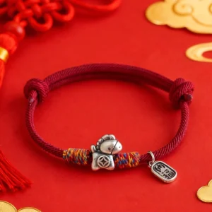 Year of the Horse red string bracelet with 999 sterling silver Fu charm on festive red gold backdrop