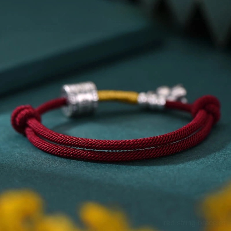 Red string horse zodiac bracelet flat lay view with yellow foliage background