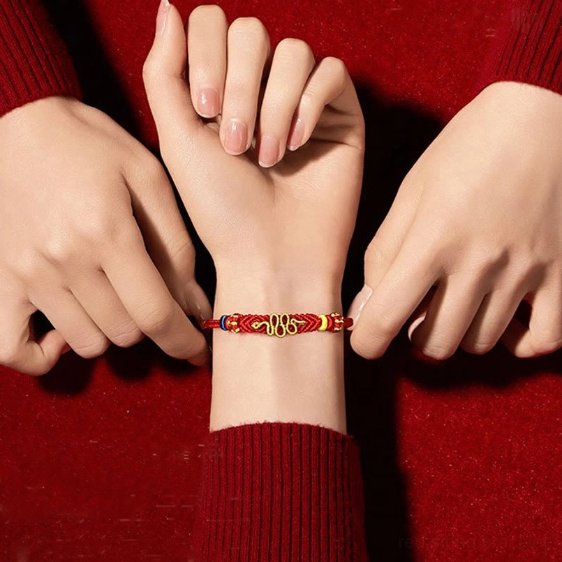 Adjusting red protective bracelet on wrist with multiple hands, overhead close-up of full design