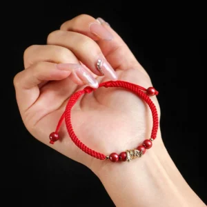 First person hand worn view of Year of Snake cinnabar red string protection bracelet