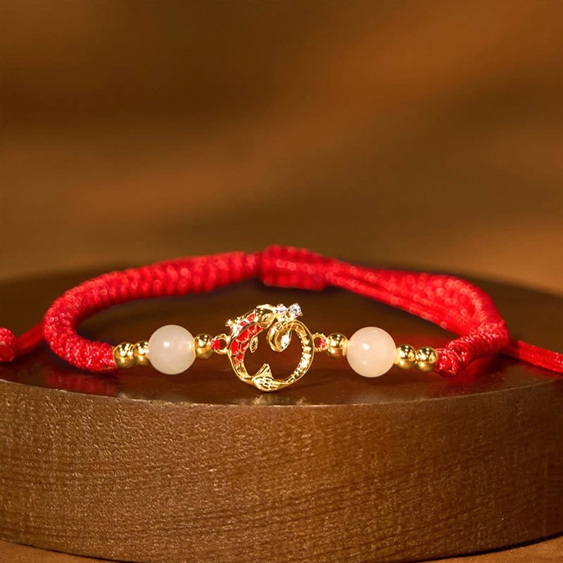 Hetian jade red string protection bracelet with light jade beads and gold snake charm flat lay