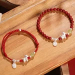 Year of the Horse red string beaded bracelet flat lay on wooden tabletop