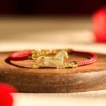 Year of the Horse charm red string lucky bracelet flat lay on wooden table