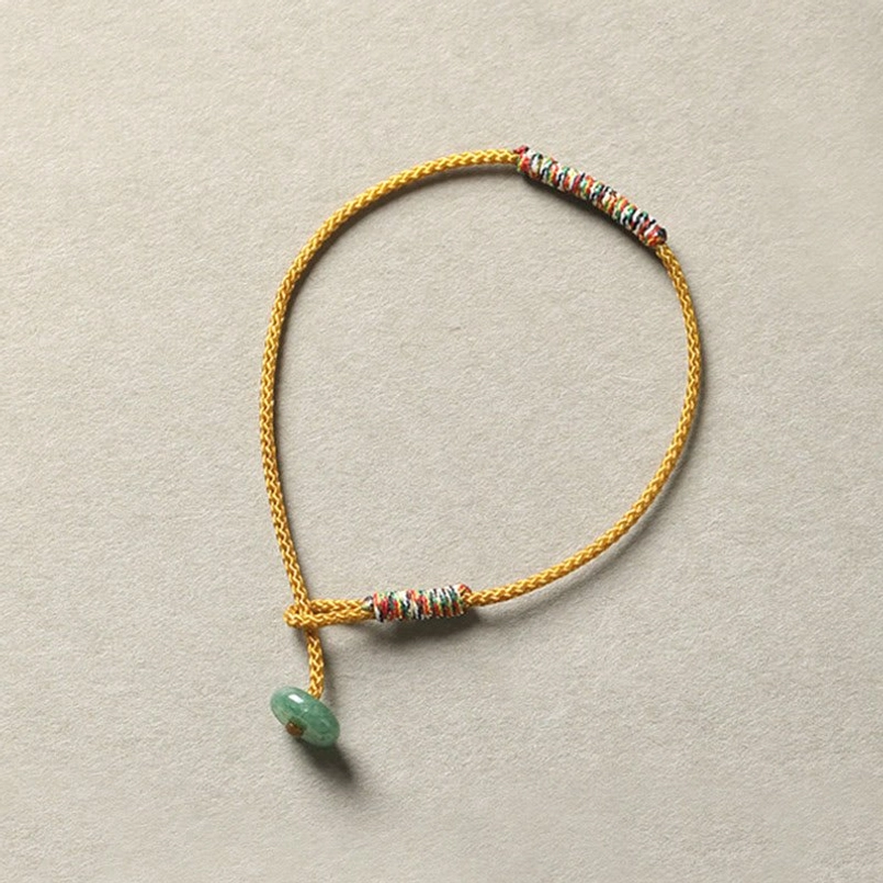 Yellow Tibetan braided bracelet with green aventurine pendant and beaded rope wrap detail
