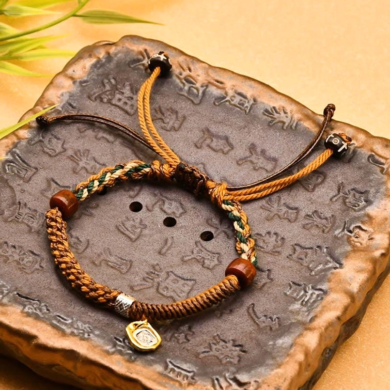 Yellow Tibetan braided Zakiram goddess of wealth red string bracelet on vintage stone tray