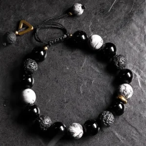 Yin Yang black obsidian lava rock bracelet oblique top view on dark stone table