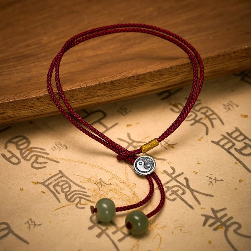 Side view of Yin Yang red string bracelet showing braided cord and silver meditation charm