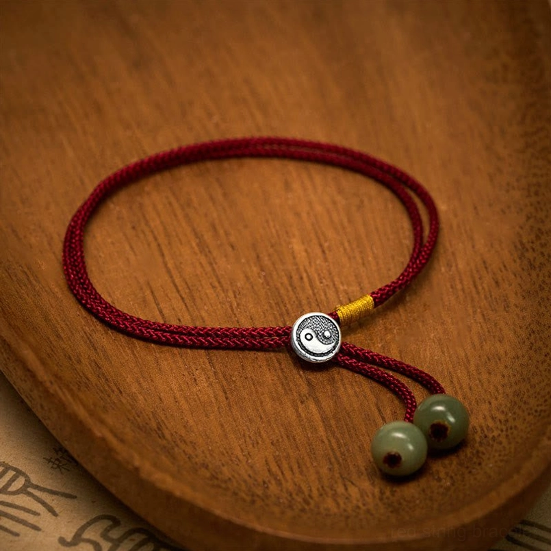 Adjustable red string Yin Yang bracelet with sterling silver charm and green jade details