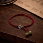 925 Sterling Silver Yin Yang Red String Bracelet with green jade beads on dark wood background