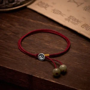 925 Sterling Silver Yin Yang Red String Bracelet with green jade beads on dark wood background