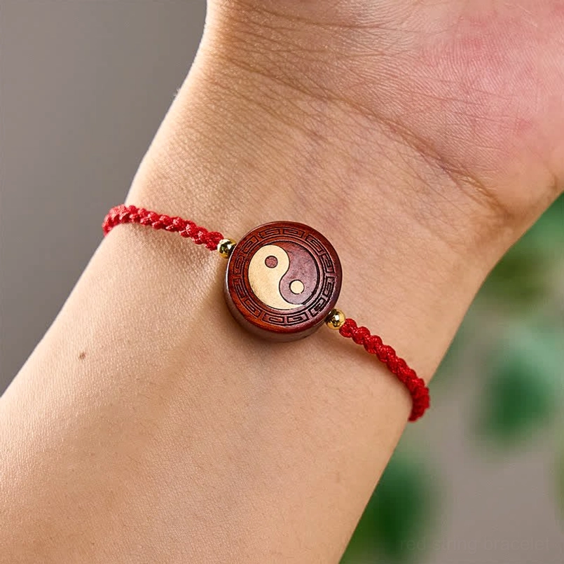 Red string yin yang bracelet worn on wrist, adjustable fit demonstration on human wrist