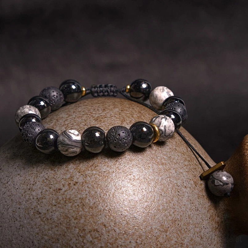 Three quarter top view of yin yang stone red string bracelet on ceramic spherical display prop